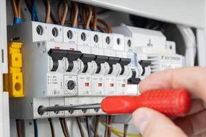 Electrician Testing Circuit Breaker with Red Handle Screwdriver photo