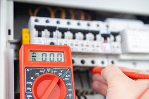 Electrician Measuring Voltage with Multimeter in Circuit Breaker Panel photo