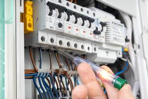 Hand Testing Electrical Circuit with Voltage Tester photo