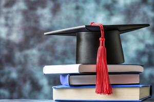A graduation cap sits on top of a stack of books photo