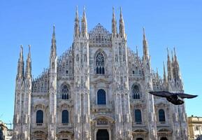 a dove flies in front of the Milan Cathedral, officially the Metropolitan Cathedral of the Nativity of the Blessed Virgin Mary, is the cathedral of the Archdiocese of Milan photo