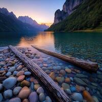 Tranquil mountain lake at sunset with colorful stones and logs photo