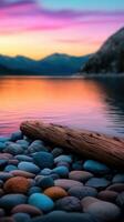 Tranquil sunset over calm lake with pebbles and a log on the shore photo