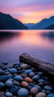 Serene sunset over calm waters with pebbles along the shoreline photo