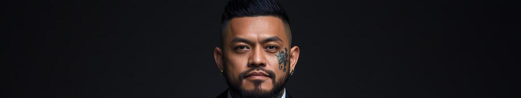 Man with a defined beard and facial tattoo posing against a dark background photo