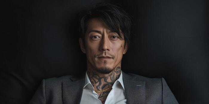 Tattooed man in suit relaxing on a black couch in a modern setting photo