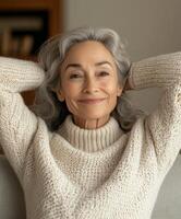 Older woman relaxing at home in cozy sweater with a warm smile photo