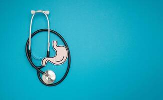 A stethoscope and stomach shape made from paper are over a blue background photo