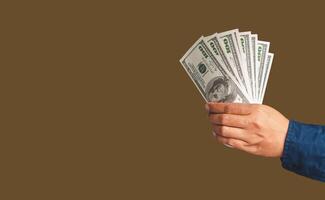 Close-up of hand holding US banknotes while standing in the studio with a brown background photo
