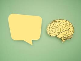 Yellow speech bubble and brain shape made from paper on a green background photo