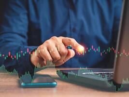 Hand of a businessman pointing to graph stock on virtual screen while sitting on the table in the office photo