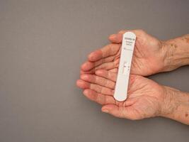 Senior woman hands holding Covid-19 Negative test result with SARS-COV-2 Saliva Antigen Rapid Test Kit photo
