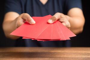 Man in casual holding a red envelope. Close-up photo
