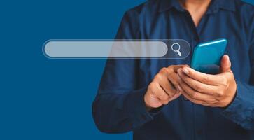 Close-up of hand a man using a mobile phone search for information interest on search engine website while standing on a blue background photo