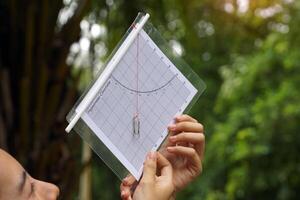 A simple clinometer made from paper is a device for easily measuring the height of objects such as trees, buildings, or tall buildings using the principles of trigonometry and Pythagoras' theory. photo