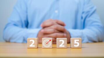 Businessman showing wooden cube from 2025. New year resolution, goal, plan, and action concept. Target plan and mission annual. Happy new year 2025 background with goal icon. photo