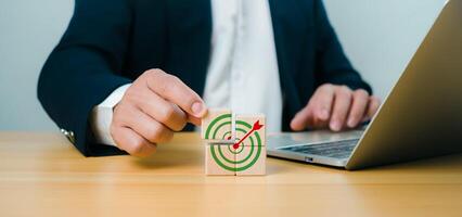 Male hand putting stack of wooden blocks with target icon on wooden table white background copy space, Business goals and objective concepts, Business competition. photo