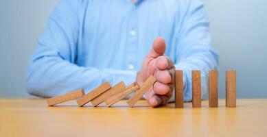 Businessman hand Stopping Falling wooden Blocks or Dominoes, Business, Risk Management, Solution, Insurance and strategy Concepts, Risk and strategy in business. photo