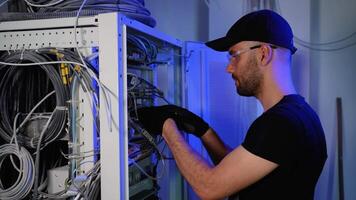 It engineer is working with internet equipment and wires in server room video