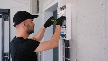 Electrician works in a switchboard with an electrical connecting cable video