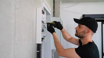 Electrician works in a switchboard with an electrical connecting cable video