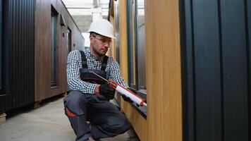 Worker using of foam when installing windows in prefabricated house video