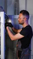 It engineer is working with internet equipment and wires in server room. Vertical video