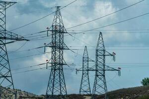 High voltage towers with sky background. Power line support with wires for electricity transmission. High voltage grid tower with wire cable at distribution station. Energy industry, energy saving photo