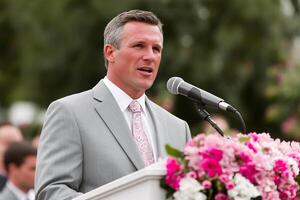 Man in Suit Speaking at Podium with Microphone and Flowers photo