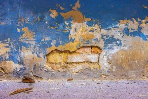 Old damaged broken shabby red brick wall of an old building. Brick texture with scratches and cracks. Grunge background with cracked grey blueish stucco. Close up. Copy space photo