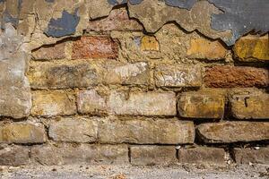 Old damaged broken shabby red brick wall of an old building. Brick texture with scratches and cracks. Grunge background with cracked grey blueish stucco. Close up. Copy space photo