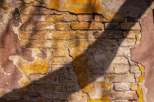 Closeup of a weathered bricks stone wall cracks and patina. Rough rustic texture and details of the aged surface, perfect for use in background and design projects. Urban decay aesthetic photo