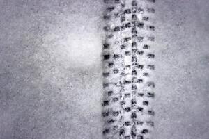 Detailed bicycle tire tread mark on fresh snow. Bike track pattern, texture left in a winter environment. Monochrome tire print on snow, providing a contrast of black against white. Copy space photo