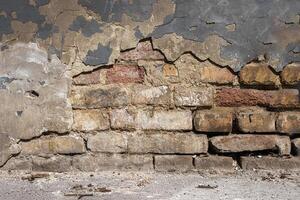 Old damaged broken shabby red brick wall of an old building. Brick texture with scratches and cracks. Grunge background with cracked grey blueish stucco. Close up. Copy space photo