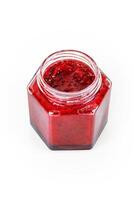 Top view of fresh, vibrant red currant berry jam in an open glass jar, perfect for breakfast spreads or desserts. Closeup. Copy space. Isolated on white background. photo