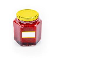 Hexagonal glass jar of homemade red currant berry or cranberry jam with a gold lid and blank label. Isaolated on white background. Copy space. photo
