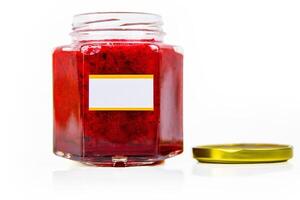 An open hexagonal glass jar of homemade red currant berry or cranberry jam with a gold lid beside it. White blank label for custom text. Copy space. Isolated on white background photo