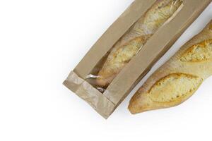 Two freshly baked baguettes, one wrapped in brown paper bag, Artisan French baguettes with crispy crusts in paper packaging. Isolated on a white background. Closeup. Clipping path. Copy space photo