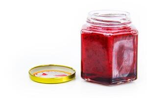 An open hexagonal glass jar of homemade red currant berry or cranberry jam with a gold lid beside it. Freshly made wild berries jelly. Copy space. Isolated on white background. photo