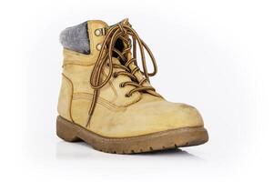 Single vintage durable yellow leather hiking boot with laces in a worn look. One beige used military shoe with thick sole. Isolated on white background. Studio light. Copy space photo