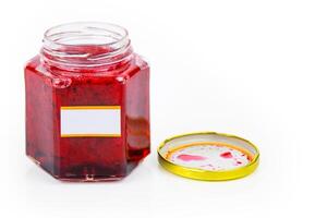 An open hexagonal glass jar of homemade red currant berry or cranberry jam with a gold lid beside it. White blank label for custom text. Copy space. Isolated on white background photo