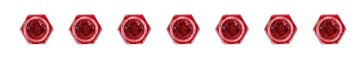 Row of seven opened hexagonal glass jars of homemade red currant berry or cranberry jam. Copy space. Isolated on white background. photo