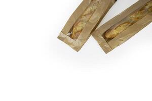 Two freshly baked baguettes, wrapped in brown paper bag, Artisan French baguettes with crispy crusts in paper packaging. Isolated on a white background. Closeup. Copy space photo