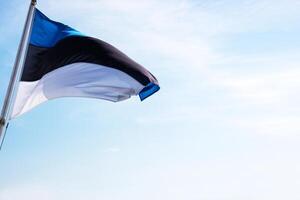 National Estonian flag waving against a partly cloudy sky, symbolizing national pride and identity with distinct horizontal blue, black, and white stripes. Copy space photo