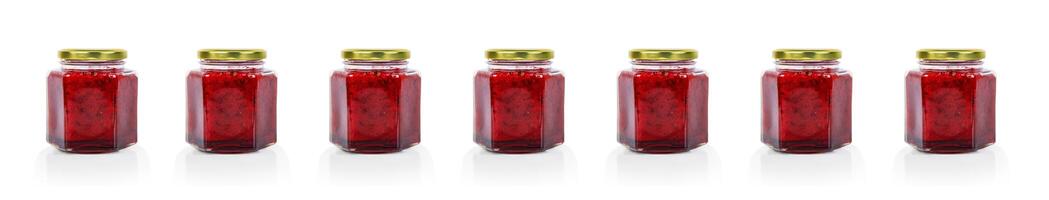 Row of seven hexagonal glass jars of homemade red currant berry or cranberry jam sealed with a gold colored metal lids. Copy space. Isolated on white background. photo