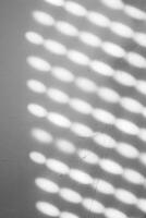 Blurred light spots, shadows from the blinds on the concrete wall on a sunny day, Natural shadow pattern on a textured white wall, formed by filtered sunlight. Copy space photo