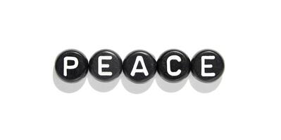 Black round beads with white letters spelling peace on white background for mindfulness and harmony concepts. photo
