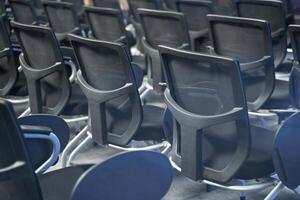 Empty conference room with rows of modern black office chairs arranged in neat alignment at corporate meeting venue photo