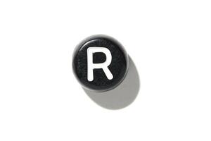 Vintage black typewriter key with r letter casting a shadow on a white background for minimalist design concepts photo