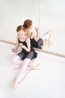 Young ballerina enjoying a cupcake in a dance studio with mirror reflection and ballet attire. photo
